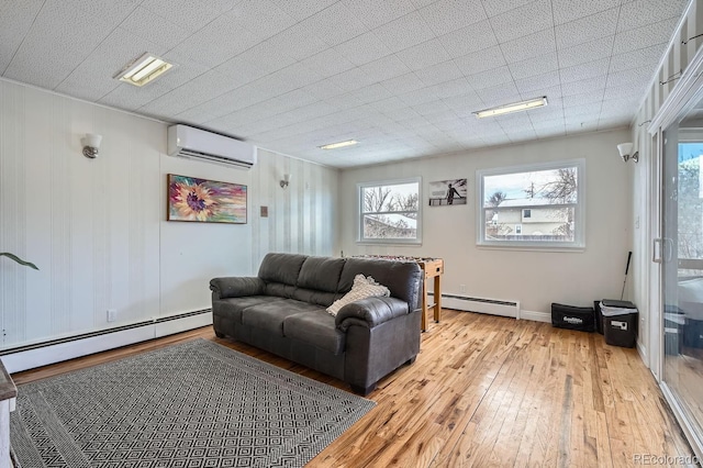 living room featuring a baseboard heating unit, light wood-style flooring, a healthy amount of sunlight, and a wall mounted AC