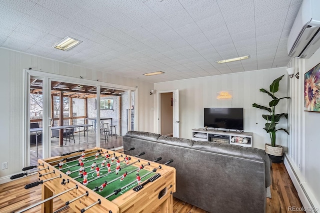 game room with wood finished floors, a wall mounted AC, and a baseboard radiator