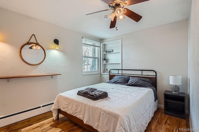 bedroom featuring ceiling fan, wood finished floors, a textured wall, and a baseboard radiator