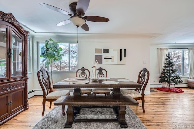 dining space with light wood-type flooring, a ceiling fan, and a baseboard radiator