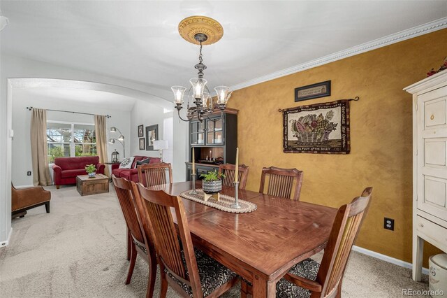 dining space featuring arched walkways, light colored carpet, a chandelier, and baseboards