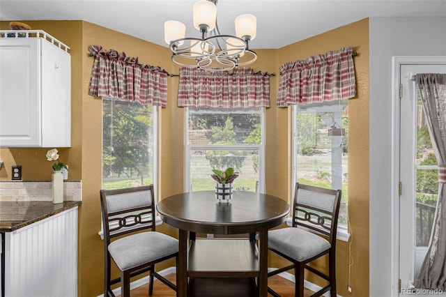 dining area featuring a chandelier, plenty of natural light, and a textured wall