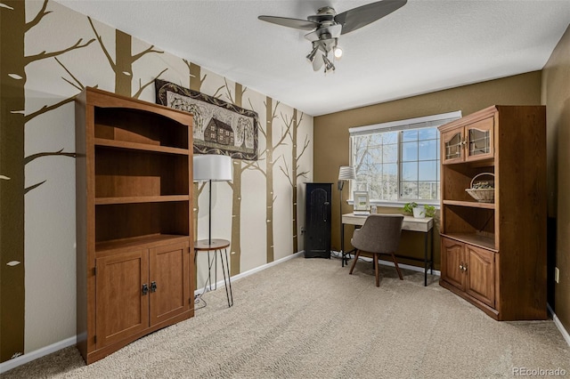 office area with light colored carpet, a ceiling fan, and baseboards