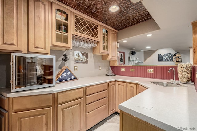 kitchen with a sink, glass insert cabinets, light brown cabinets, an ornate ceiling, and light countertops