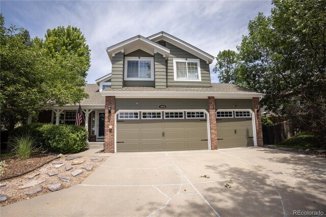 craftsman-style house featuring brick siding, driveway, a garage, a shingled roof, and fence