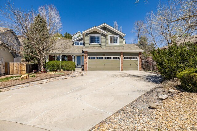 view of front of property with brick siding, fence, concrete driveway, a garage, and a shingled roof