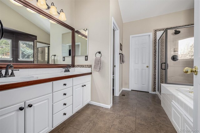 bathroom featuring plenty of natural light, a stall shower, baseboards, and double vanity