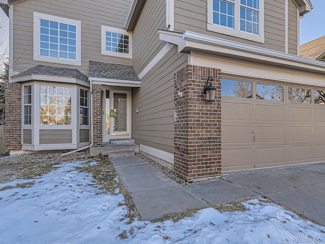 snow covered property entrance featuring a garage