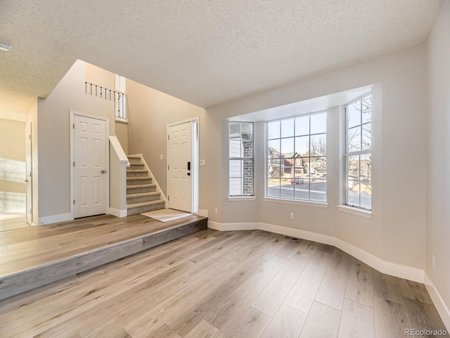 empty room with light wood-type flooring and a textured ceiling