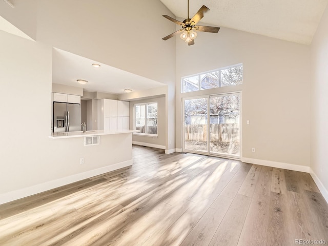 unfurnished living room featuring ceiling fan, high vaulted ceiling, and light wood-type flooring