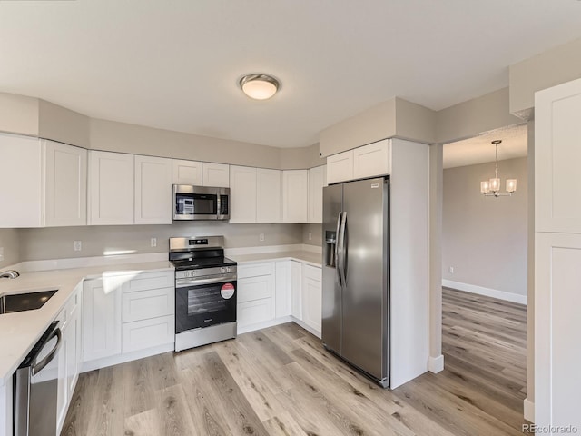 kitchen featuring white cabinetry, pendant lighting, stainless steel appliances, and an inviting chandelier