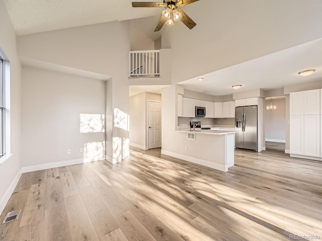 unfurnished living room with a healthy amount of sunlight, high vaulted ceiling, and light hardwood / wood-style floors