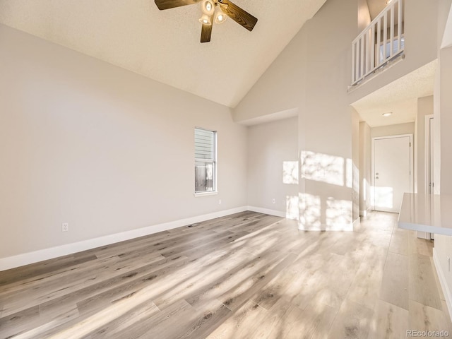 unfurnished living room with a textured ceiling, light hardwood / wood-style flooring, high vaulted ceiling, and ceiling fan