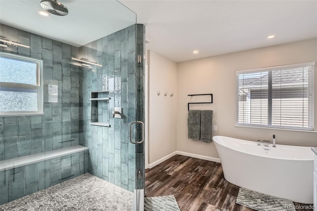 bathroom featuring baseboards, a soaking tub, wood finished floors, a shower stall, and recessed lighting