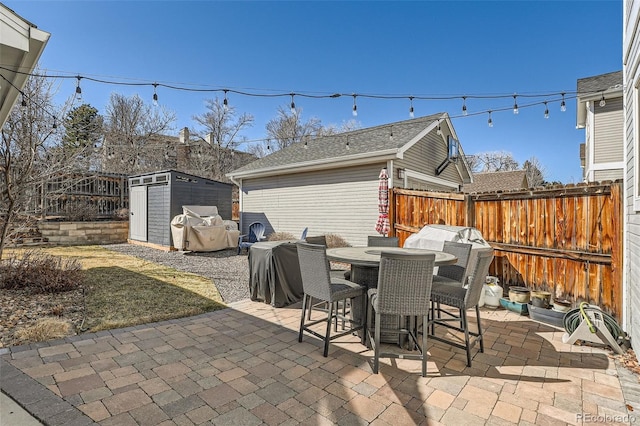 view of patio featuring an outbuilding, a shed, outdoor dining space, and fence