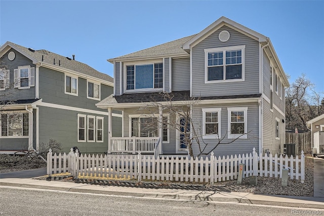 traditional-style home featuring a fenced front yard and a porch