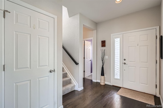 entrance foyer featuring dark wood-style flooring, stairway, and baseboards