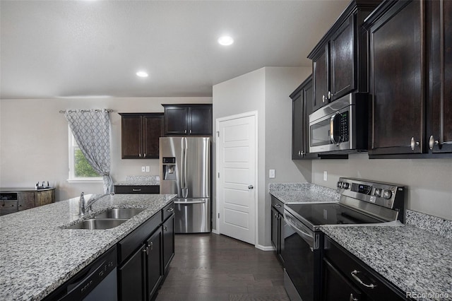 kitchen featuring appliances with stainless steel finishes, light stone counters, dark brown cabinetry, sink, and dark hardwood / wood-style floors