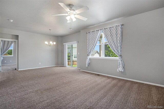 carpeted empty room with ceiling fan with notable chandelier and a wealth of natural light