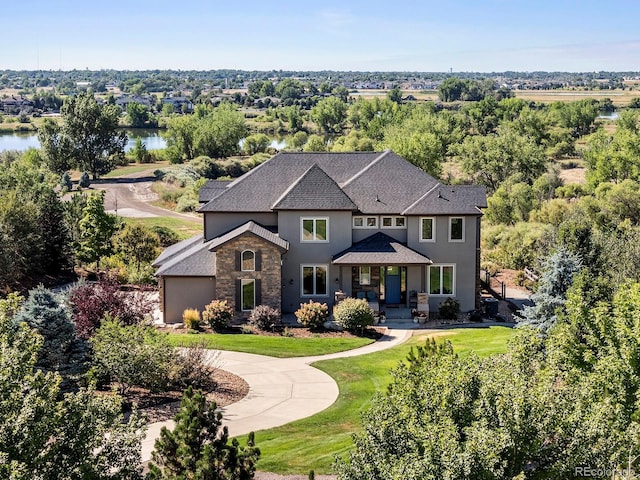 12648 Waterside Ln, Longmont, CO 80504 - view of front of property with stone siding, stucco siding, an attached garage, a front yard, and curved driveway
