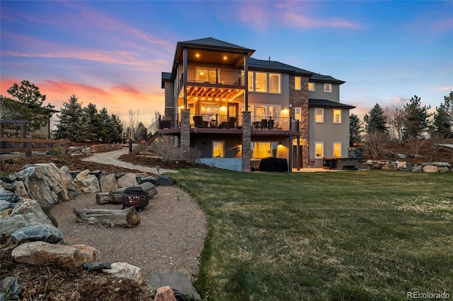 12648 Waterside Ln, Longmont, CO 80504 - back of property at dusk featuring a balcony, stucco siding, a lawn, and stairs