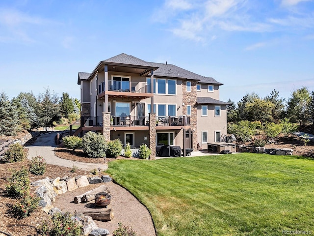 12648 Waterside Ln, Longmont, CO 80504 - rear view of property featuring a balcony, a hot tub, stucco siding, a lawn, and stone siding