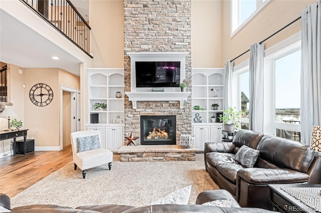 12648 Waterside Ln, Longmont, CO 80504 - living area with a stone fireplace, plenty of natural light, a towering ceiling, wood finished floors, and built in features