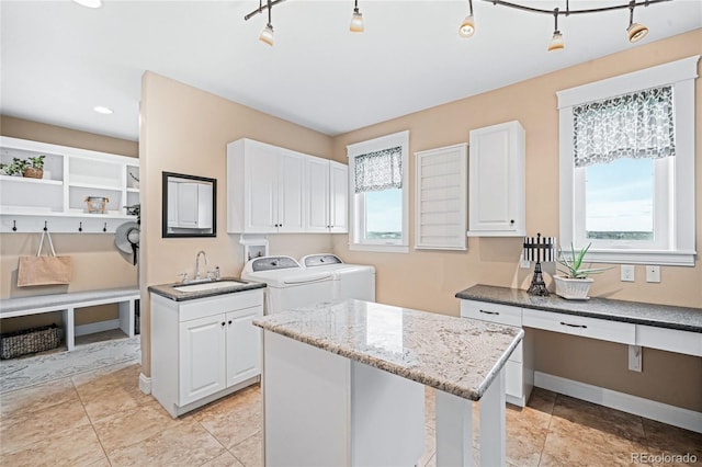 12648 Waterside Ln, Longmont, CO 80504 - kitchen with separate washer and dryer, light stone counters, white cabinets, a center island, and recessed lighting