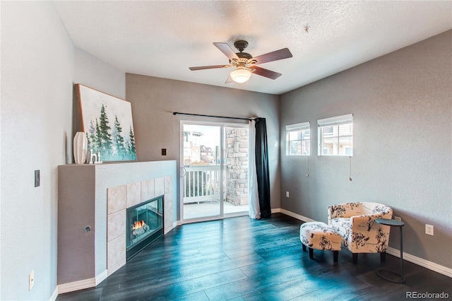 sitting room featuring a fireplace, a textured ceiling, dark hardwood / wood-style flooring, and ceiling fan