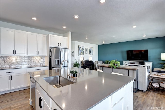 kitchen with light wood finished floors, appliances with stainless steel finishes, a sink, and white cabinets