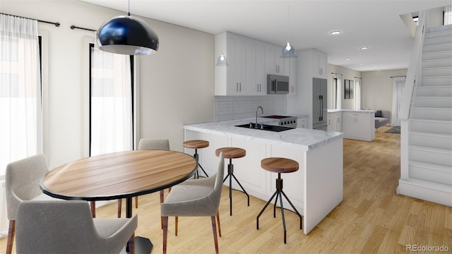 kitchen with light wood-type flooring, light countertops, backsplash, a peninsula, and appliances with stainless steel finishes