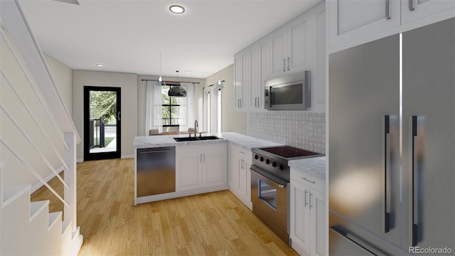 kitchen with a sink, decorative backsplash, light wood-style flooring, a peninsula, and appliances with stainless steel finishes