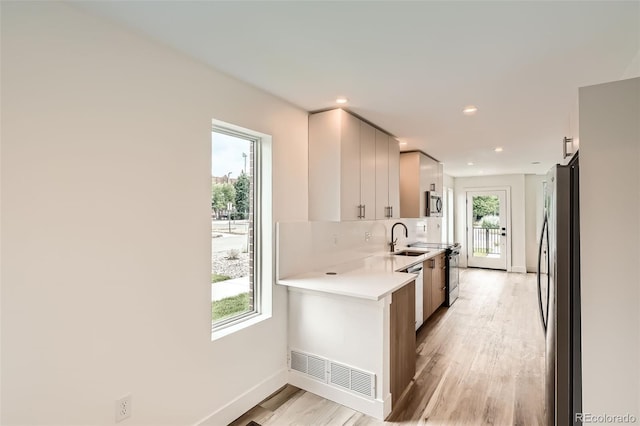 115 W 2nd Ave Unit 101, Denver, CO 80223 - kitchen with appliances with stainless steel finishes, light countertops, light wood-style floors, recessed lighting, and decorative backsplash