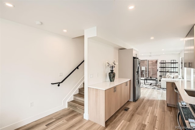 115 W 2nd Ave Unit 101, Denver, CO 80223 - kitchen featuring modern cabinets, appliances with stainless steel finishes, light wood-style flooring, light brown cabinets, and open floor plan