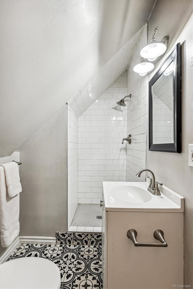 bathroom featuring tile patterned floors, vanity, toilet, and a tile shower