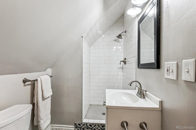 bathroom featuring toilet, vanity, and a tile shower