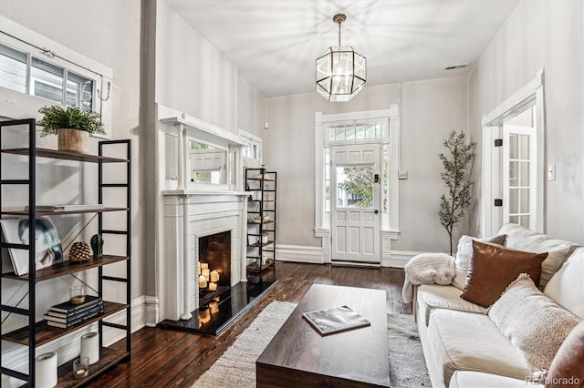 living room featuring dark wood-type flooring, a fireplace, and a chandelier