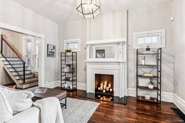 living room featuring a brick fireplace, a chandelier, and dark hardwood / wood-style flooring