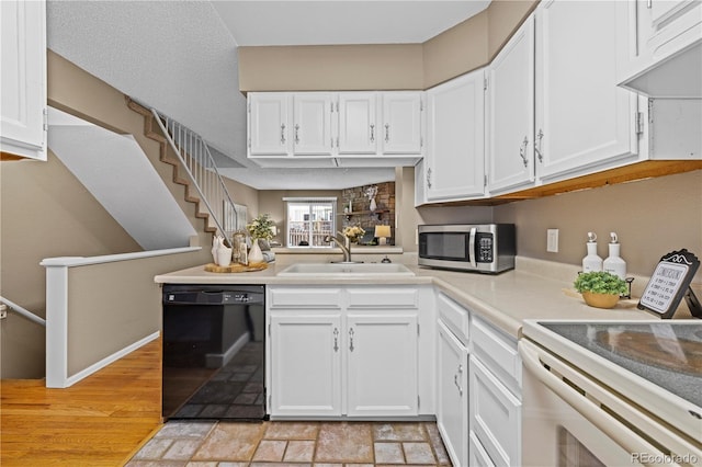 kitchen featuring premium range hood, a sink, white cabinets, black dishwasher, and stainless steel microwave