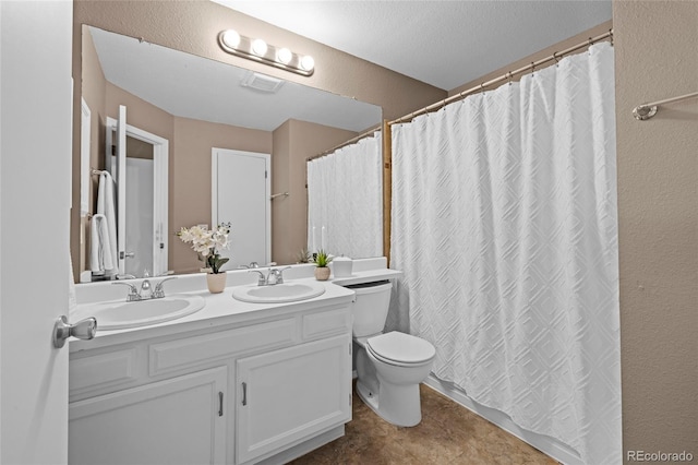 bathroom featuring double vanity, visible vents, a sink, and a textured wall