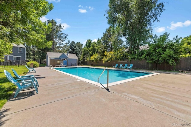 pool featuring an outbuilding, a patio area, and fence