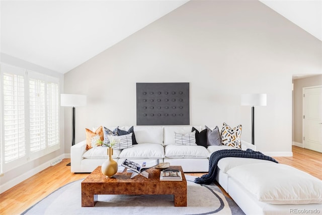 living room with high vaulted ceiling, visible vents, baseboards, and wood finished floors