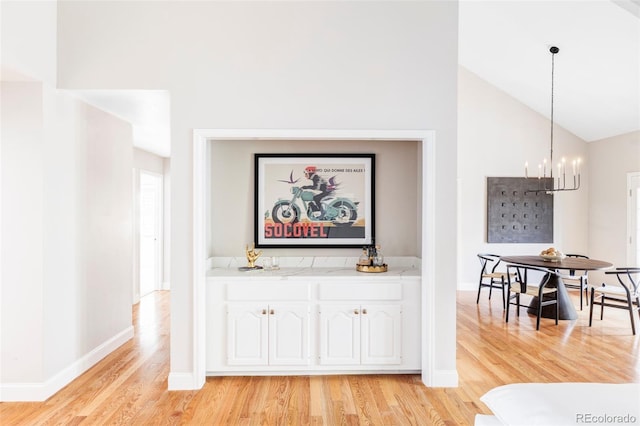 interior space featuring light wood-style floors, baseboards, hanging light fixtures, and a notable chandelier