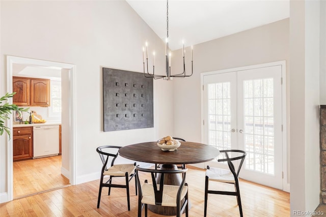 dining space featuring plenty of natural light, french doors, high vaulted ceiling, a notable chandelier, and light wood-style flooring