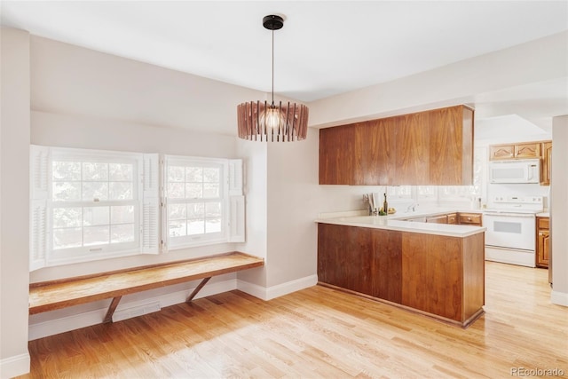 kitchen with white appliances, light countertops, a peninsula, baseboards, and light wood-type flooring