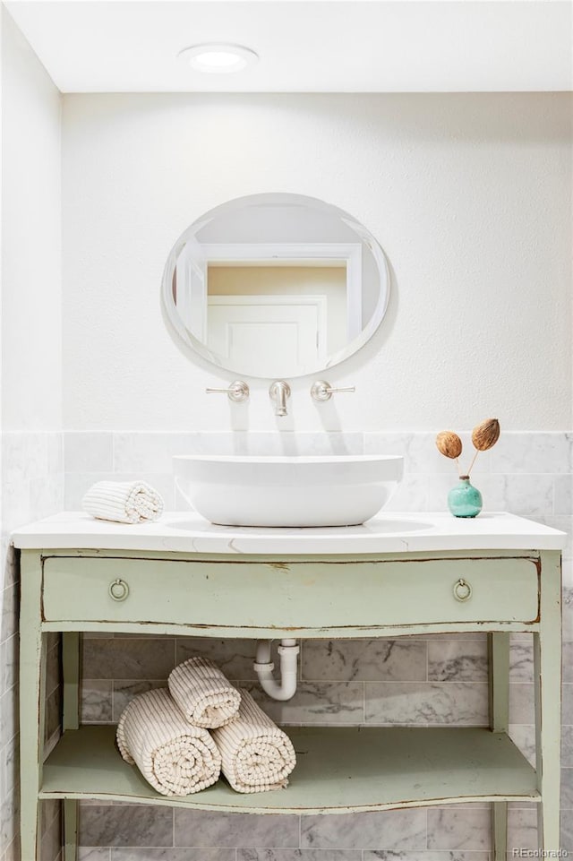 bathroom featuring vanity, wainscoting, and tile walls