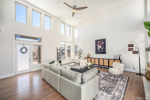 living room with recessed lighting, a high ceiling, a ceiling fan, baseboards, and hardwood / wood-style flooring