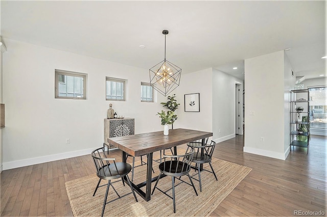 dining space with a notable chandelier, recessed lighting, wood-type flooring, and baseboards