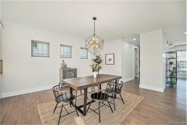 dining room with wood-type flooring, recessed lighting, baseboards, and a notable chandelier