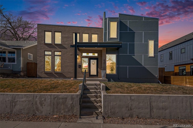 contemporary home with fence and brick siding